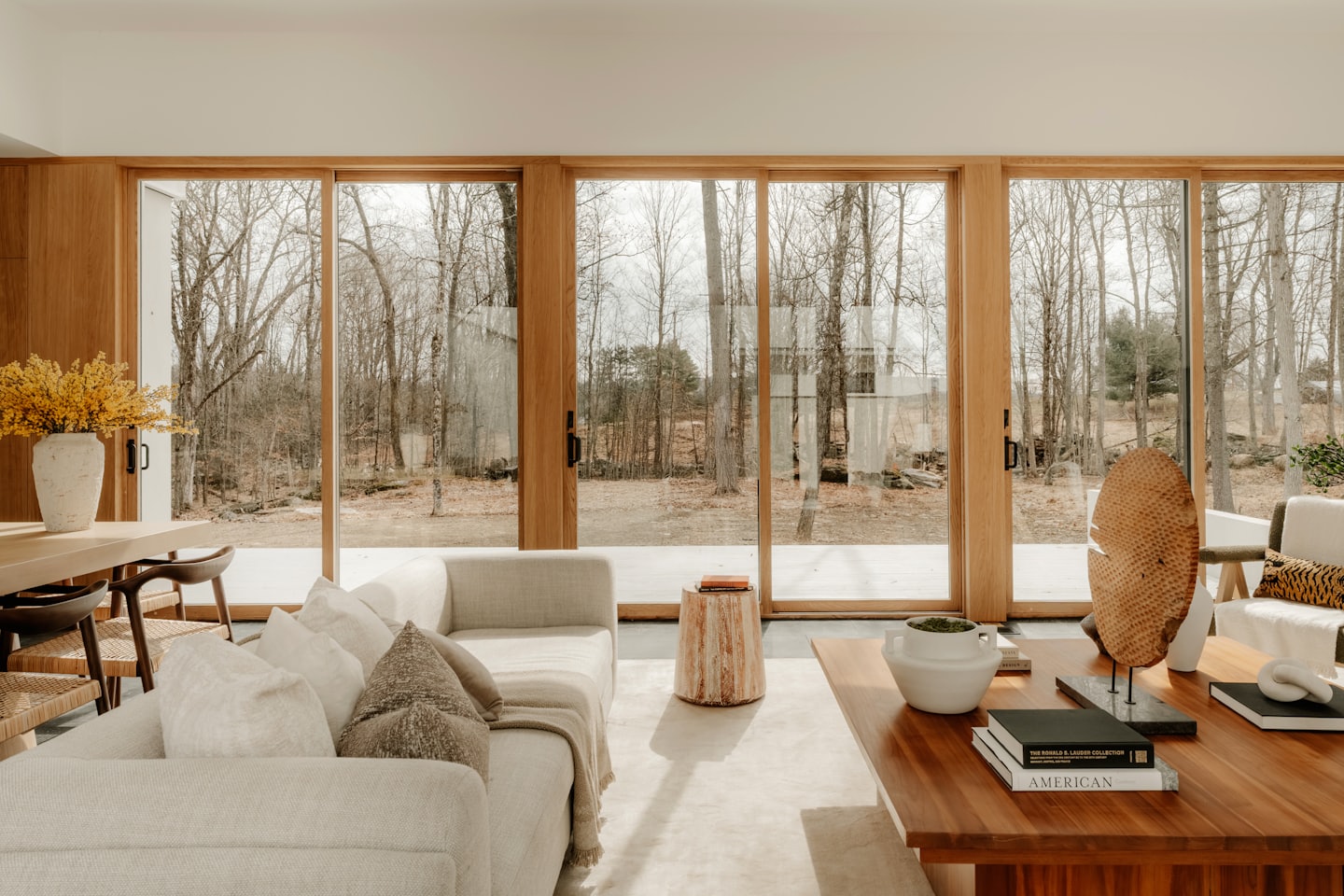 Sala de estar moderna con sofá modular y vistas a un bosque invernal.