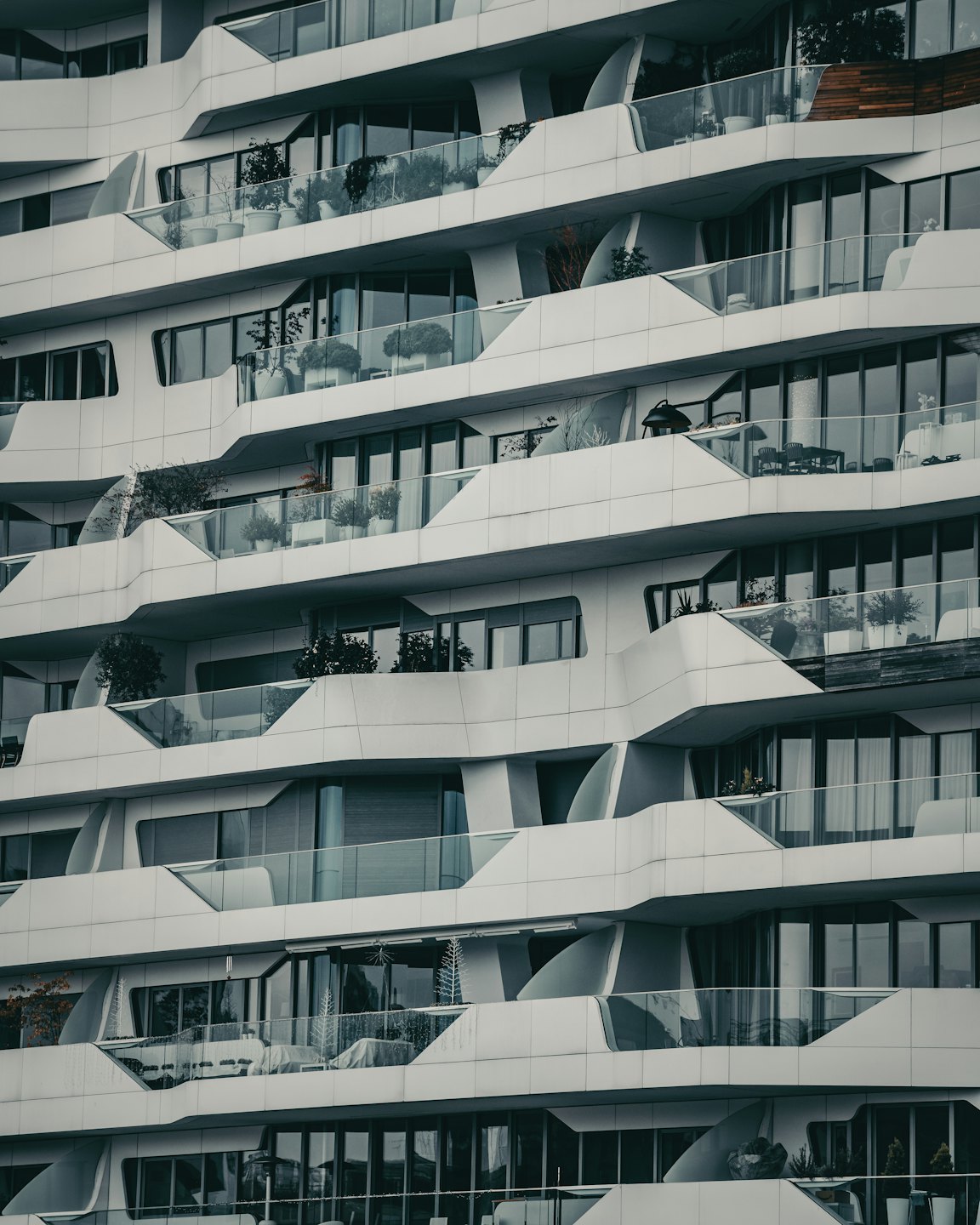 Edificio de apartamentos moderno con arquitectura curvilínea blanca y balcones de cristal.